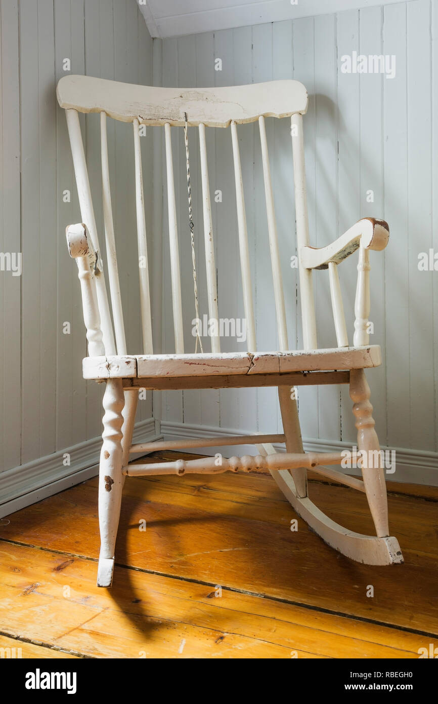 Blanco antiguo mecedora de madera pintadas en la esquina del dormitorio  principal en el piso de arriba en una antigua casa de estilo cabaña 1862  Fotografía de stock - Alamy