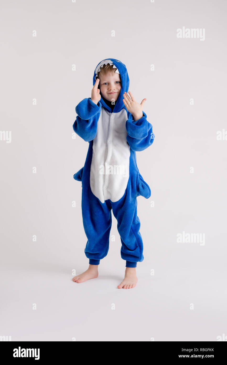 Niñito alegre posando sobre un fondo blanco en pijama, traje de tiburón  azul Fotografía de stock - Alamy
