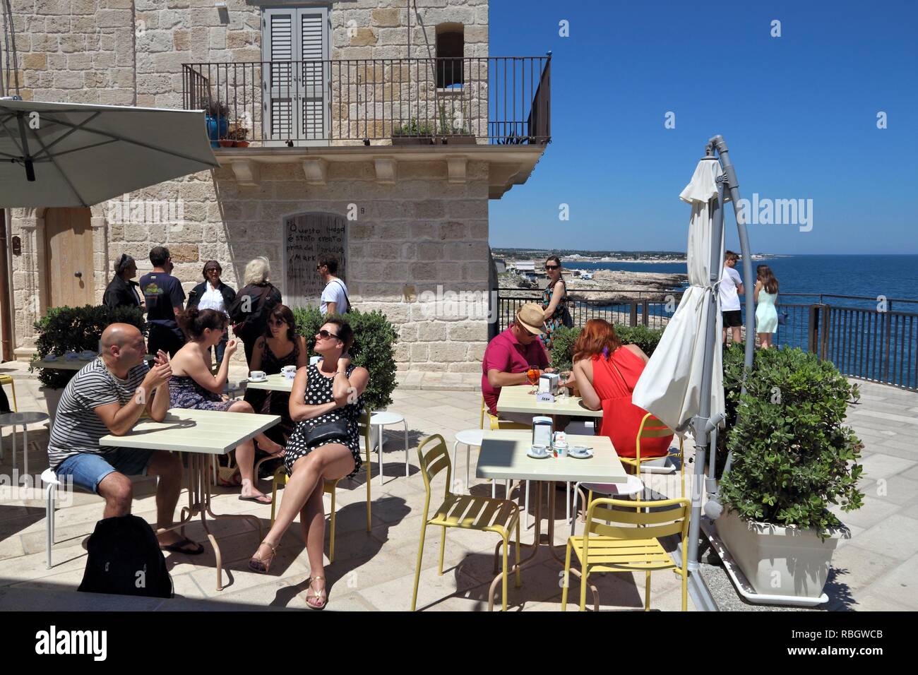 POLIGNANO A Mare, Italia - 29 de mayo, 2017: la gente se sienta en un café en Polignano a Mare Old Town en Apulia, Italia. Con 50,7 millones de visitantes anuales Italia es Foto de stock