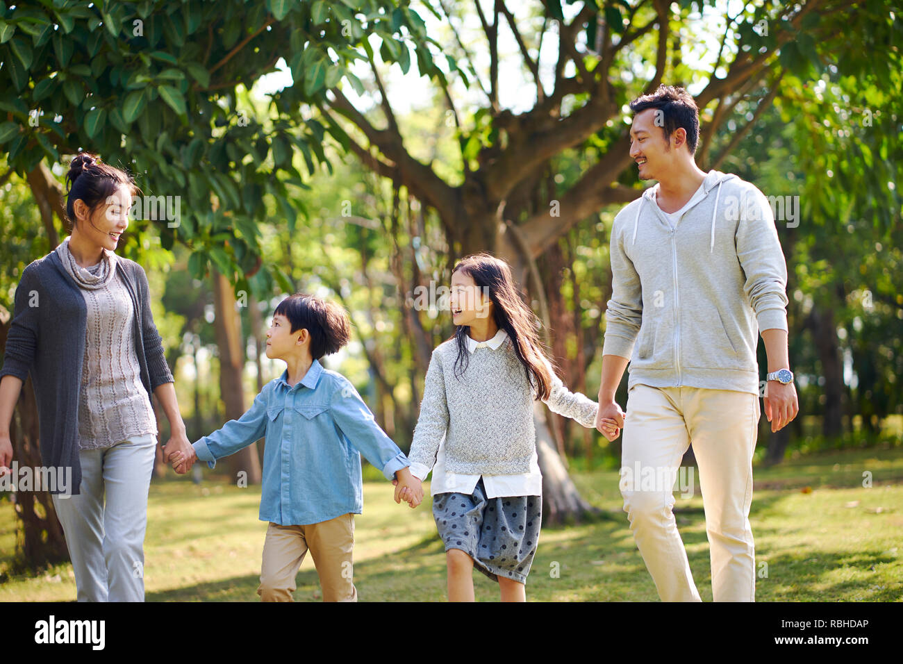 Familia con dos niños asiáticos relajantes paseos en el parque feliz y sonriente. Foto de stock