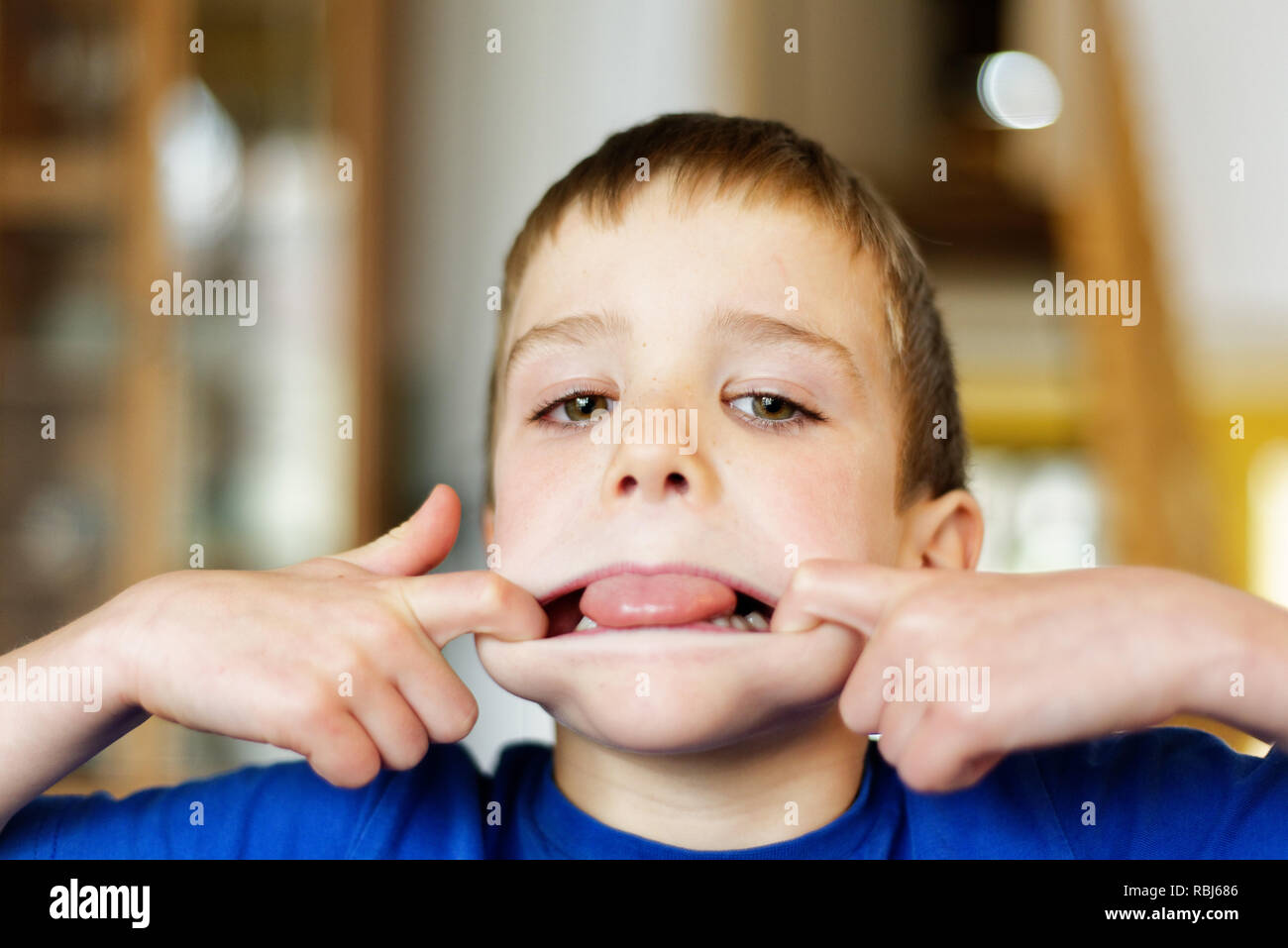 Un joven (6 años) tirando de caras en la cámara Foto de stock