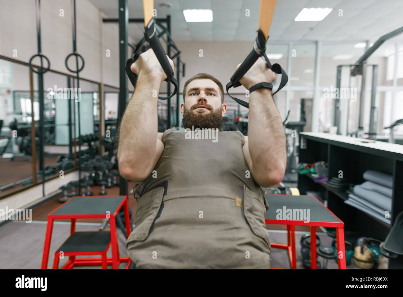 Deporte Militar, musculoso caucásico barbado hombre adulto, hacer ejercicios en el gimnasio vestida con un chaleco blindado a prueba de balas. Foto de stock