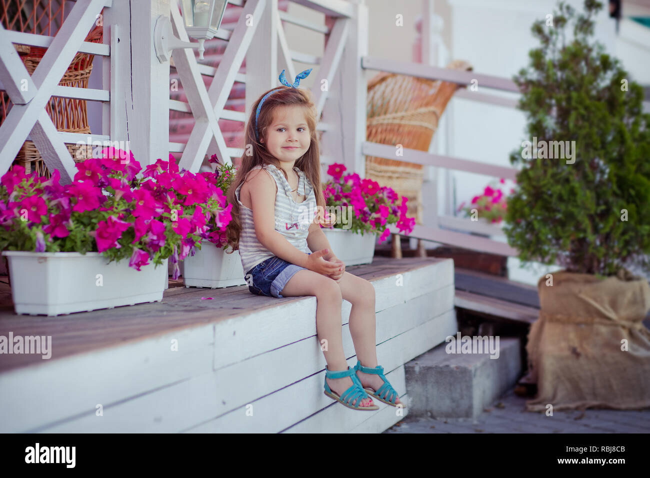 Elegante Hermoso Lindo Bebe Nina Morena Con Cabello Posando En El Jardin Lleno De Flores De Madera Vistiendo Camisetas Y Pantalones Vaqueros Diminutos Skivy Underwaist Aireado Y B Fotografia De Stock Alamy