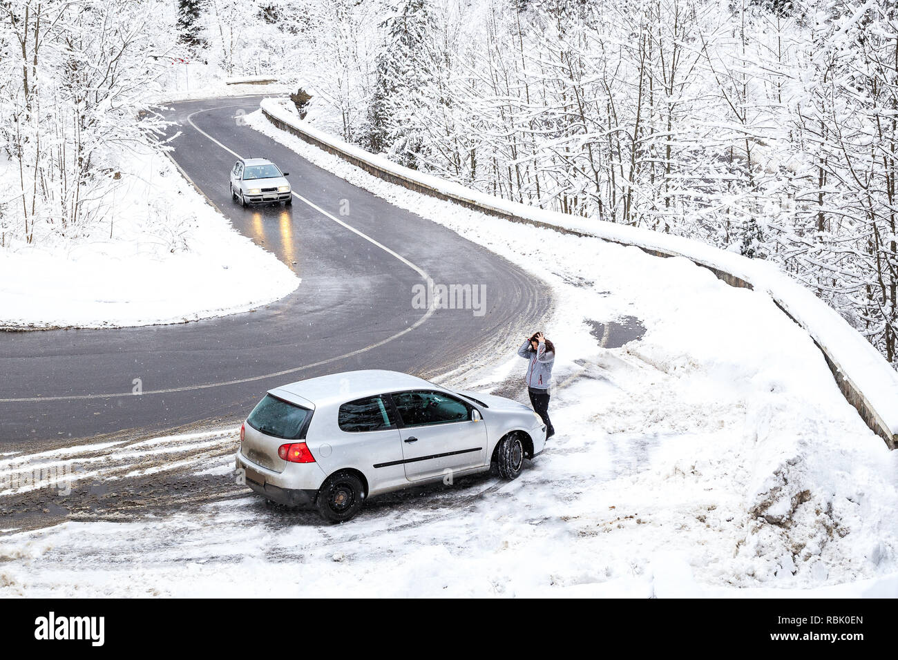 Mujer aterrorizados por el coche se rompió a través de las serpentinas de montaña en invierno. Coche rotos en la carretera. Foto de stock