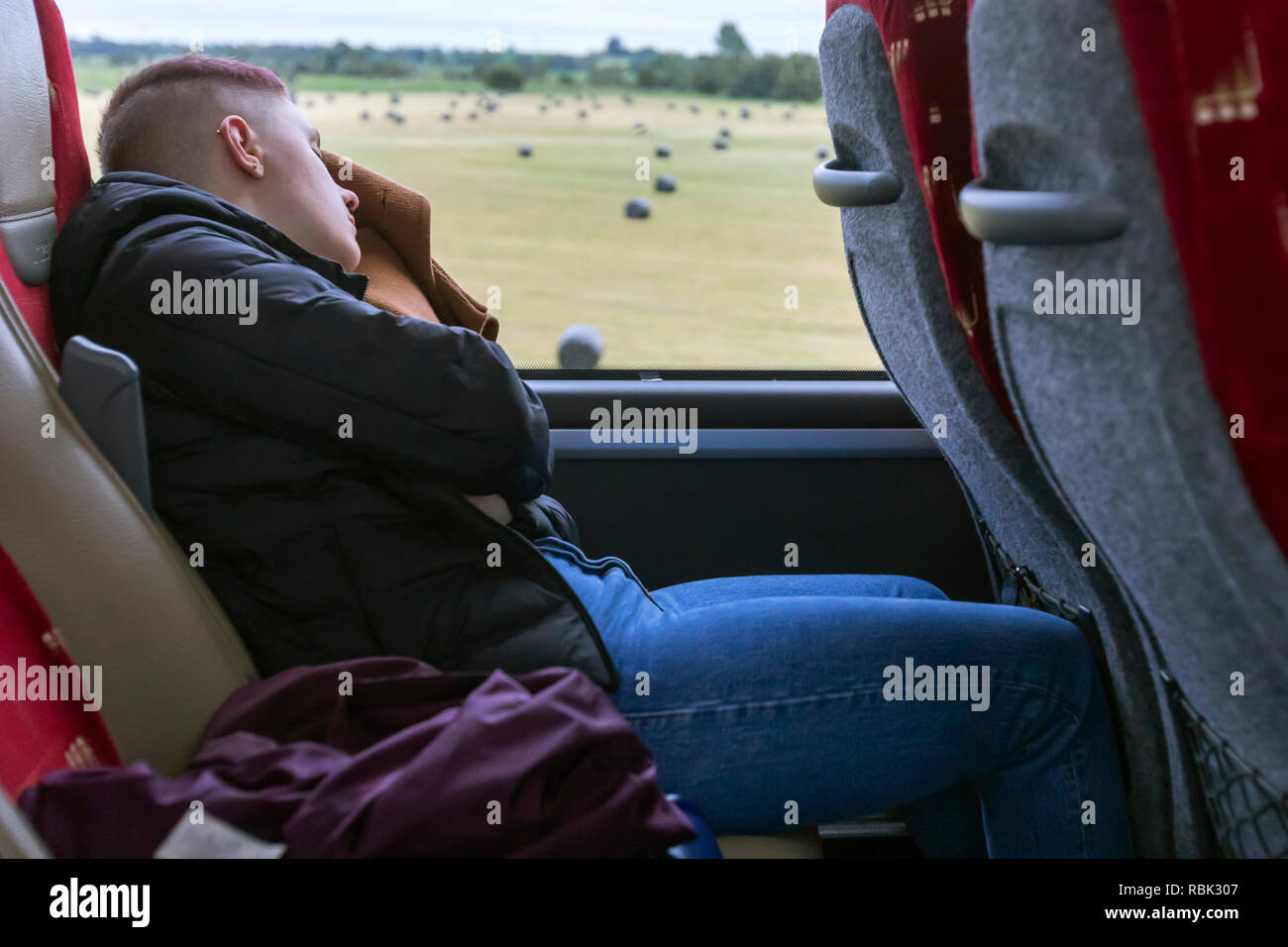Mujer joven durmiendo en un bus mientras viajaba hacia un destino en Irlanda. Foto de stock