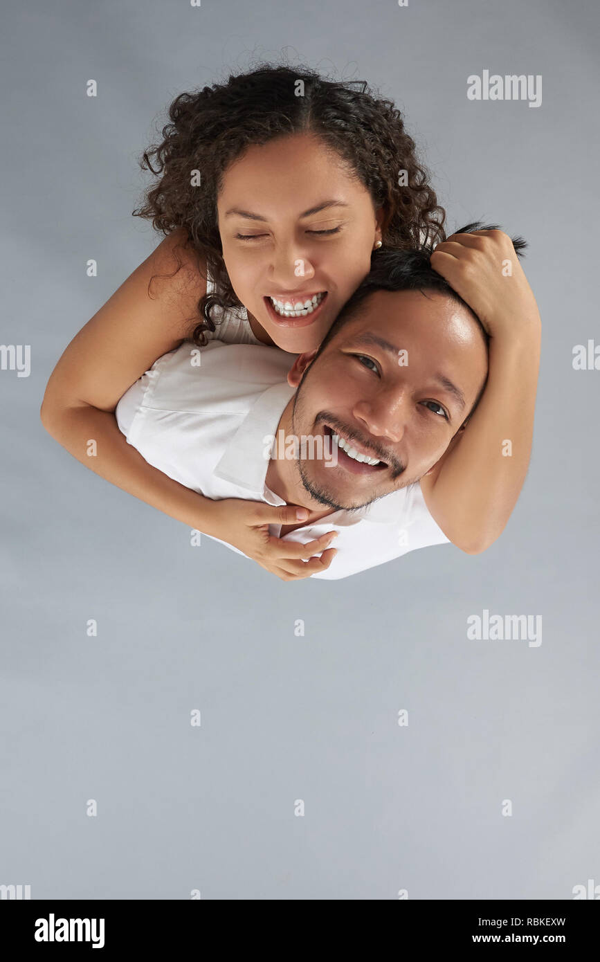 Mujer joven obsesionado con el hombre por encima de vista superior en gris de fondo studio Foto de stock