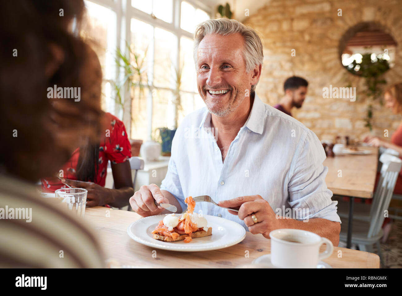 Feliz senior hombre blanco comer almuerzo con amigos en un café Foto de stock