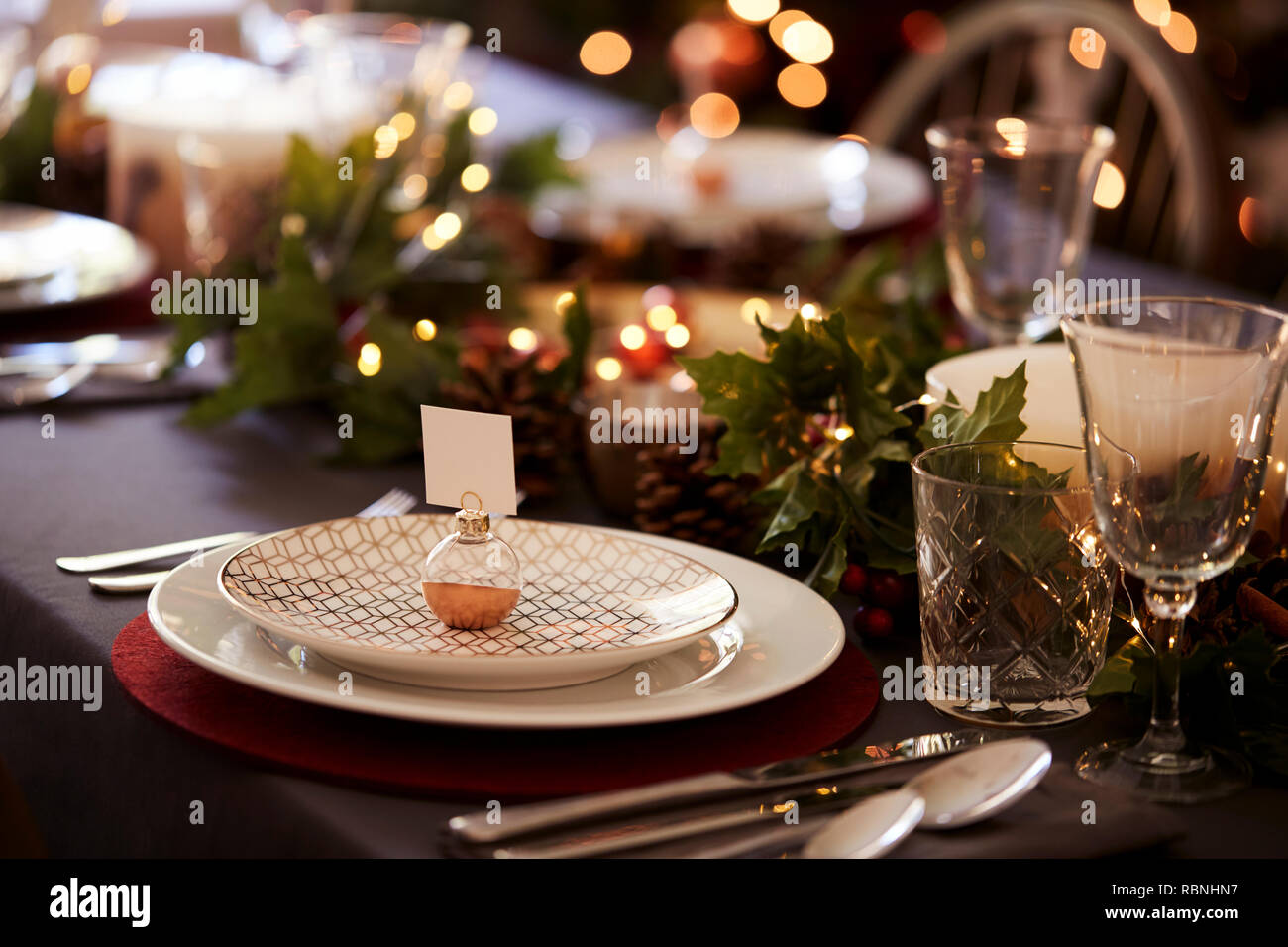 Ajuste de la tabla de Navidad con adornos de titular de tarjeta nombre organizado sobre una placa y decoraciones de mesa verde y rojo Foto de stock