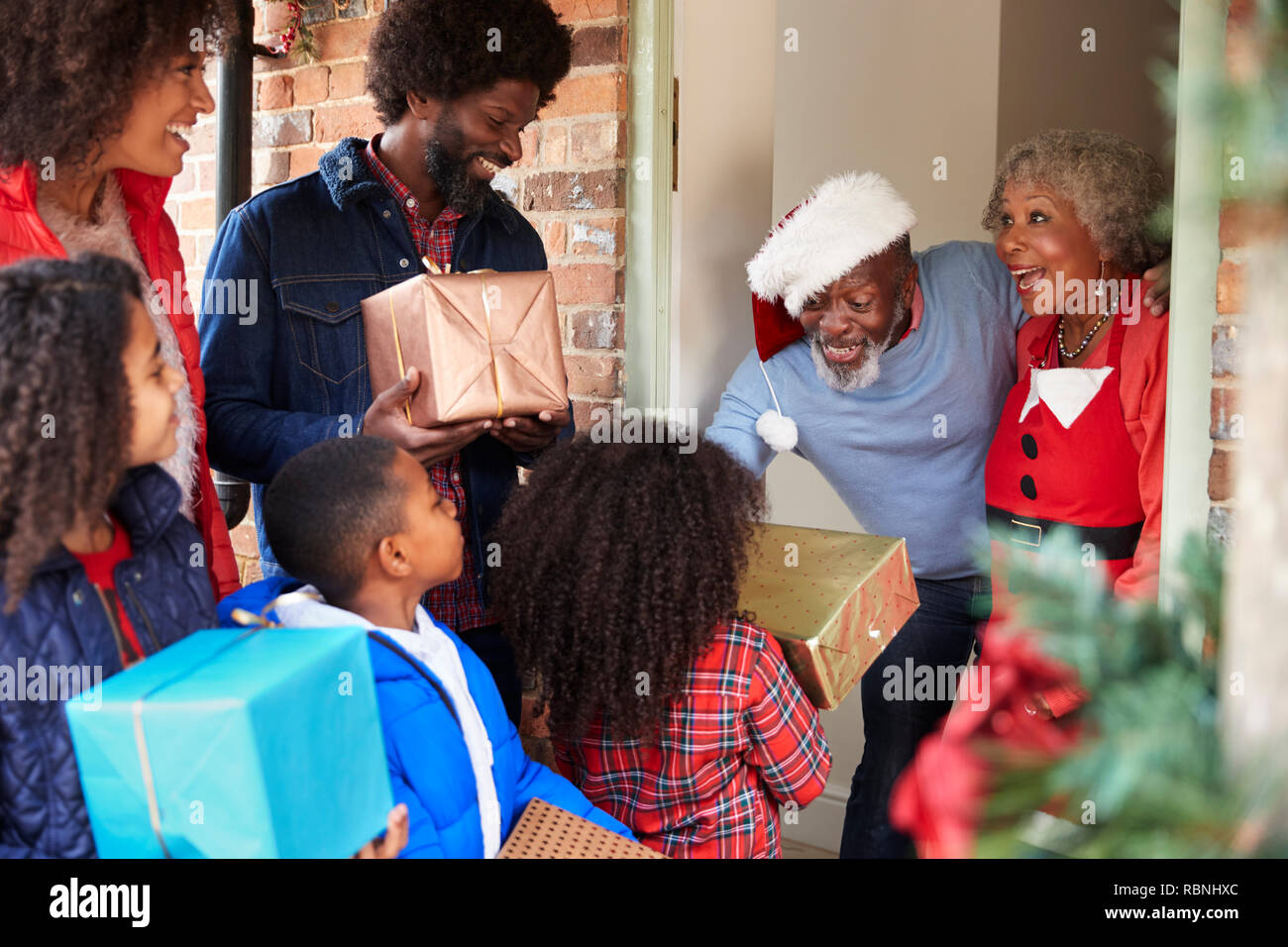 Los abuelos de la familia saludo como llegan para visitar el día de Navidad con regalos Foto de stock