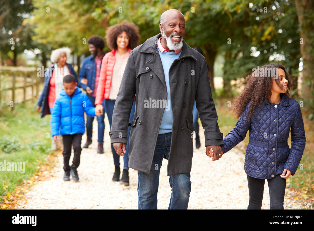 Familia de generación múltiple en otoño de caminar juntos en el campo Foto de stock