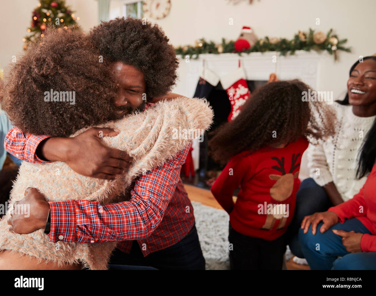 Pareja abrazarse como intercambio de regalos en Navidad en familia de generación múltiple en casa Foto de stock