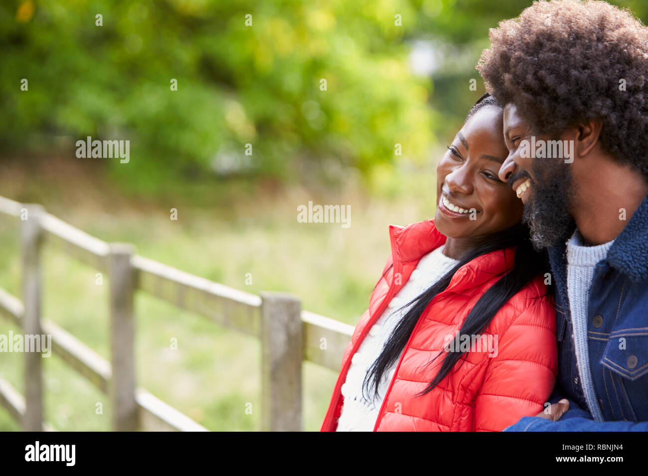 Mujer adulta negro recostada sobre el hombro de su novio, de pie en el campo, cerrar Foto de stock