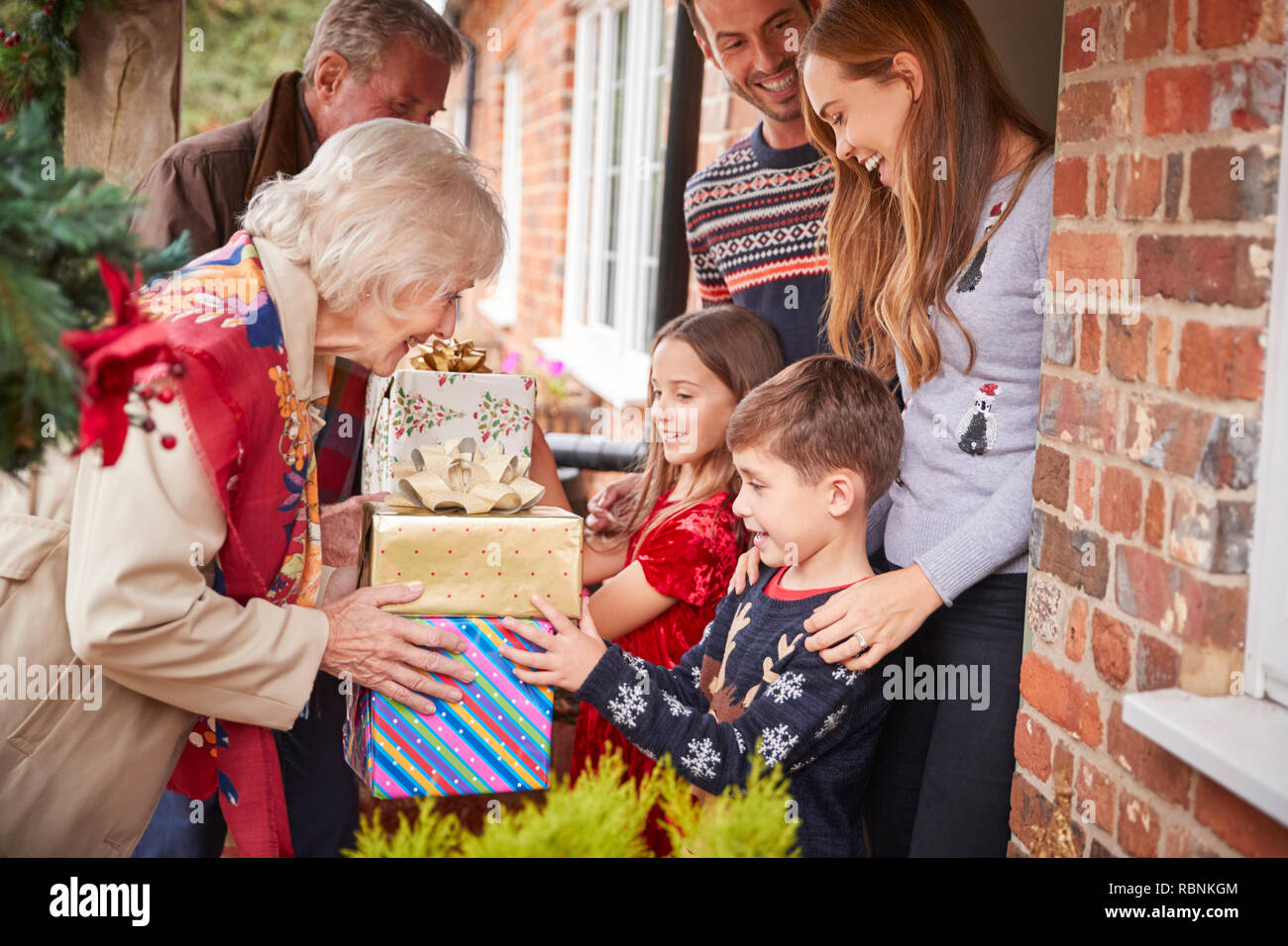Los abuelos recibida por la familia como llegan para visitar el día de Navidad con regalos Foto de stock