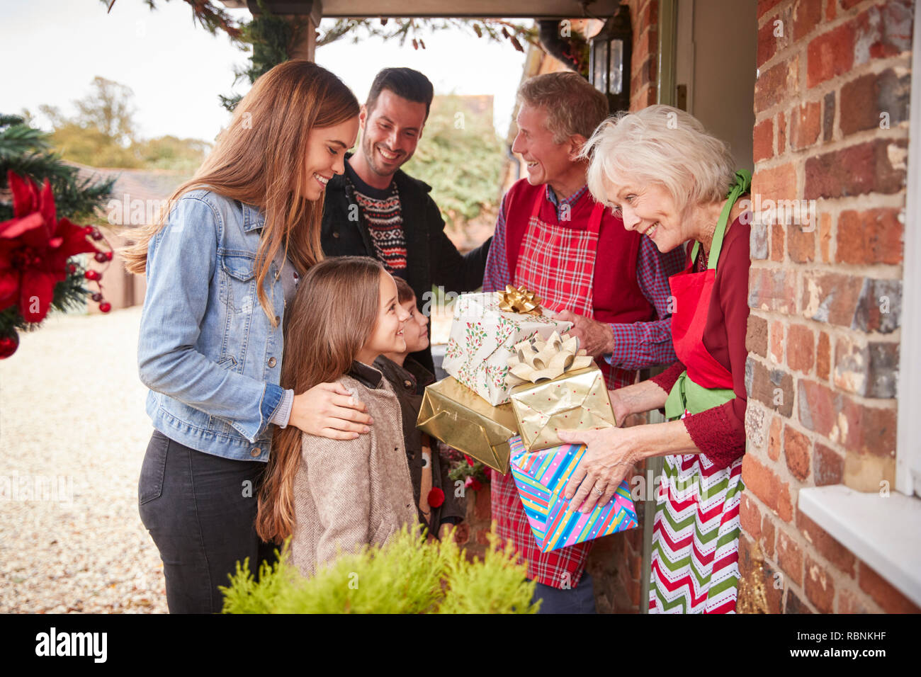 Familia ser saludado por los abuelos como llegan para visitar el día de Navidad con regalos Foto de stock