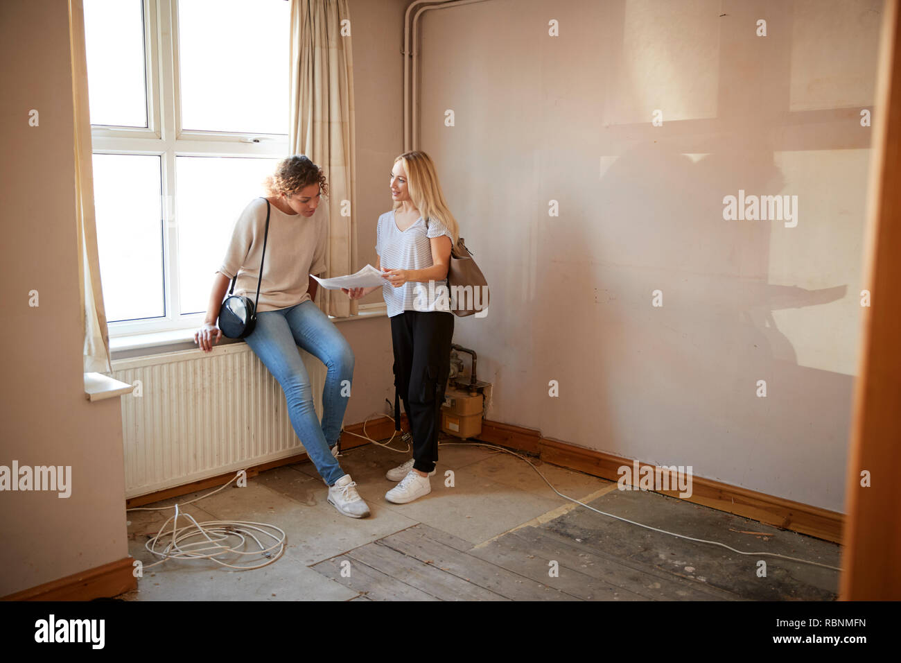 Dos amigas comprando casa por primera vez mirando la encuesta en casa habitación renovada Foto de stock