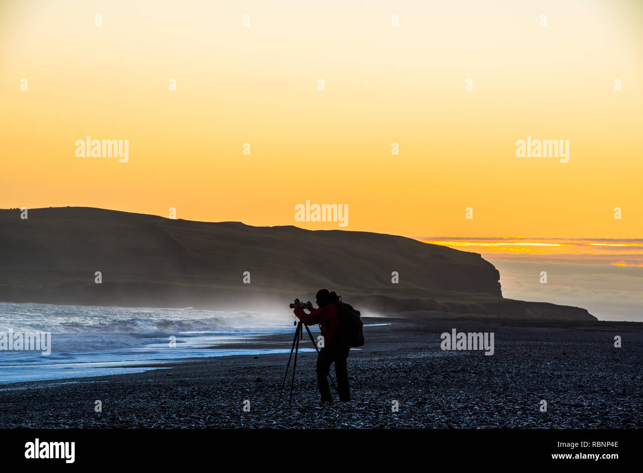 Silueta de un único fotógrafo en el océano de luz del atardecer dorado Foto de stock