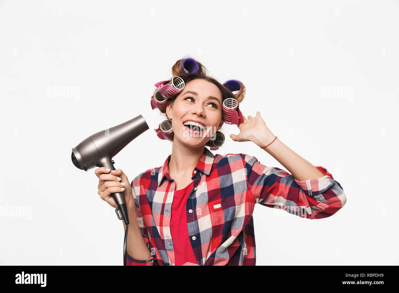 Alegre ama de casa con rulos en el cabello que se encuentran aisladas sobre  fondo blanco, utilizando un secador de pelo Fotografía de stock - Alamy