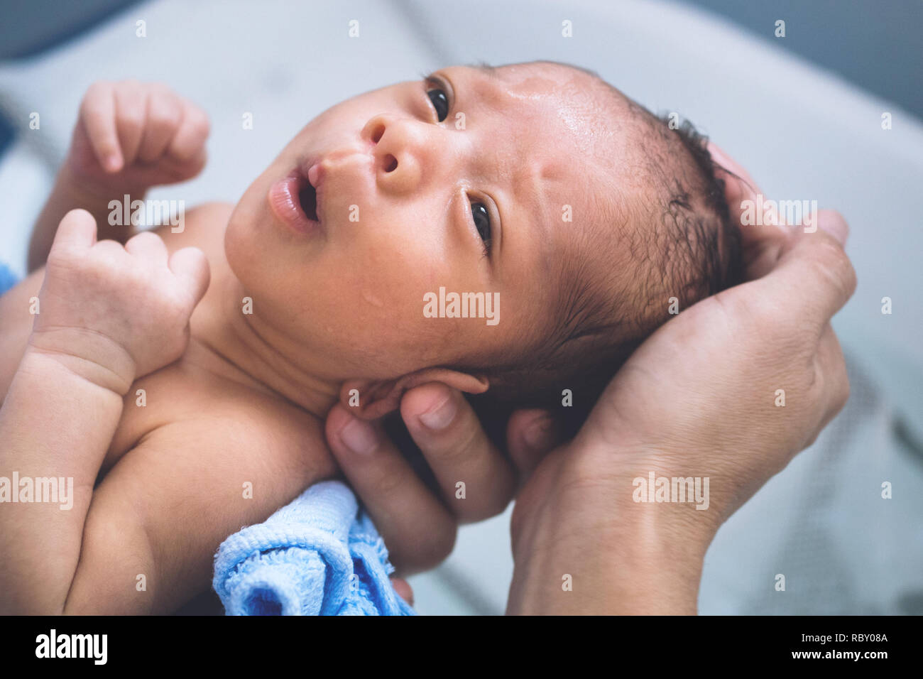 Feliz asian Baby Boy sensación de frío para tomar un baño en la primera hora de vida. madre sosteniendo y baño recién nacido en la mañana con el estilo de vida del bebé. Foto de stock