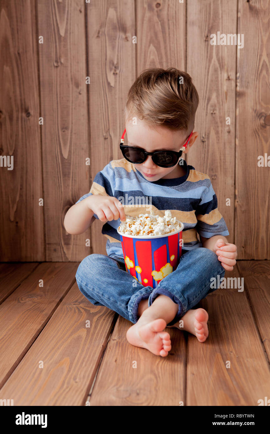 Poco chico lindo bebé niño 2-3 años , 3D IMAX cinema gafas sosteniendo la  cuchara para palomitas, comer comida rápida sobre fondo de madera. La vida  infantil para niños Fotografía de stock - Alamy