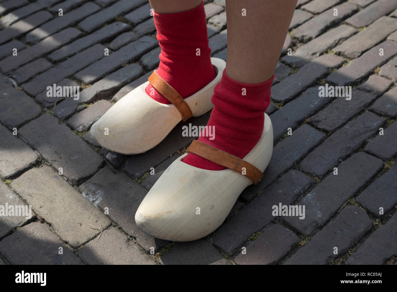 Holandés clásico zapatos de madera desgastada por una chica con calcetines rojos Foto de stock