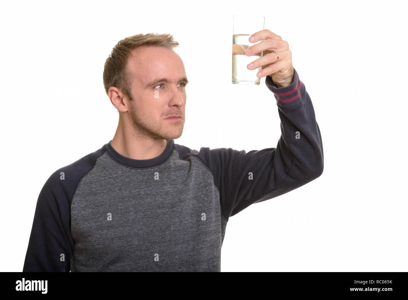 Apuesto hombre caucásica observando un vaso de agua mientras piensa Foto de stock