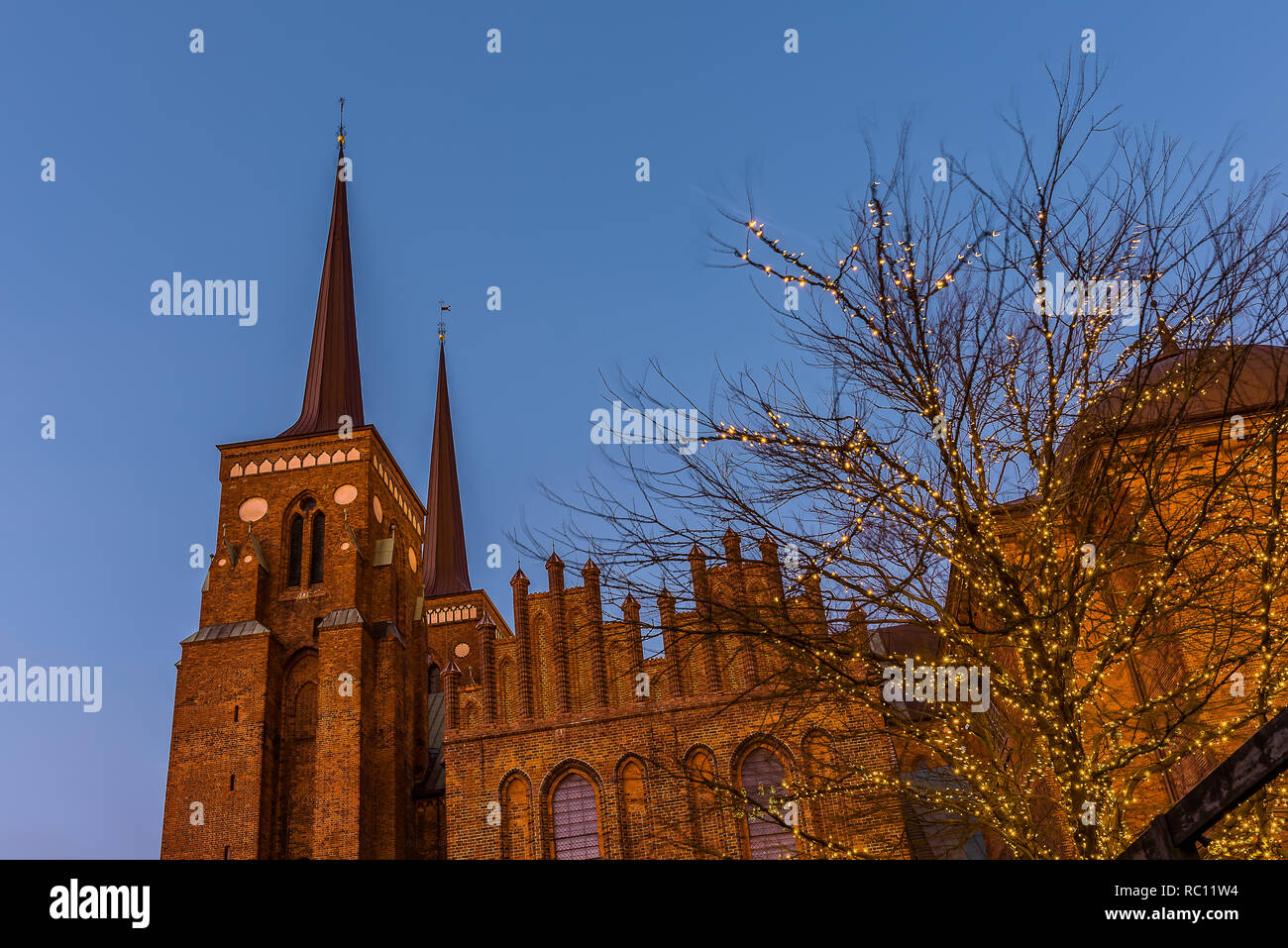 Catedral Roskilde en el suave atardecer contra el cielo azul y un árbol con bombillas, Roskilde, Dinamarca, Jaunuary 11, 2019 Foto de stock