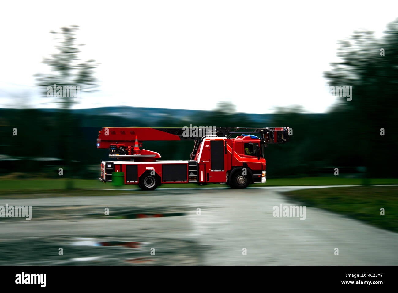 Camión de bomberos con la sirena y las luces azules de conducción rápida  sobre una carretera mojada Fotografía de stock - Alamy