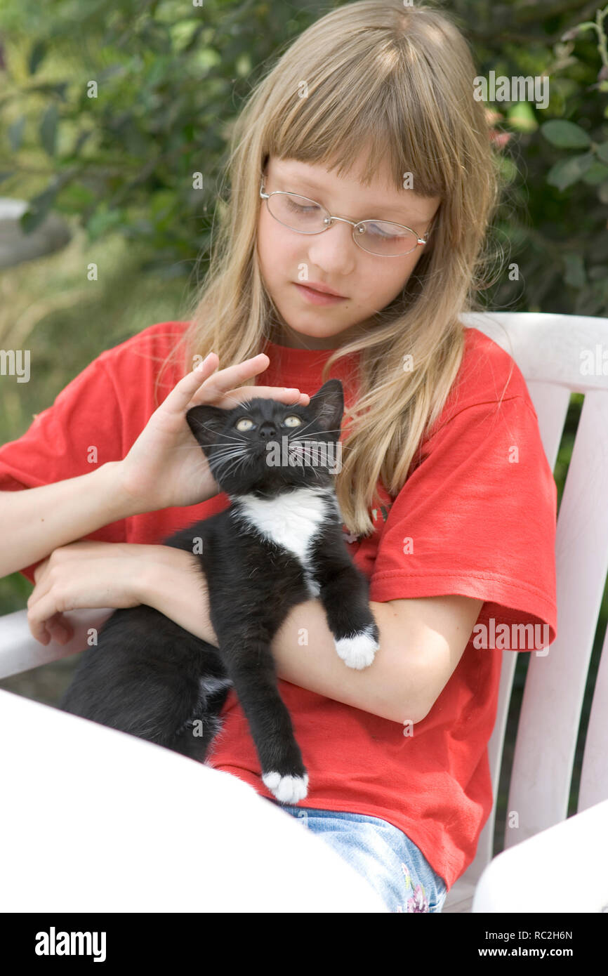 Teenie chica acariciando gato en verano fuera Foto de stock