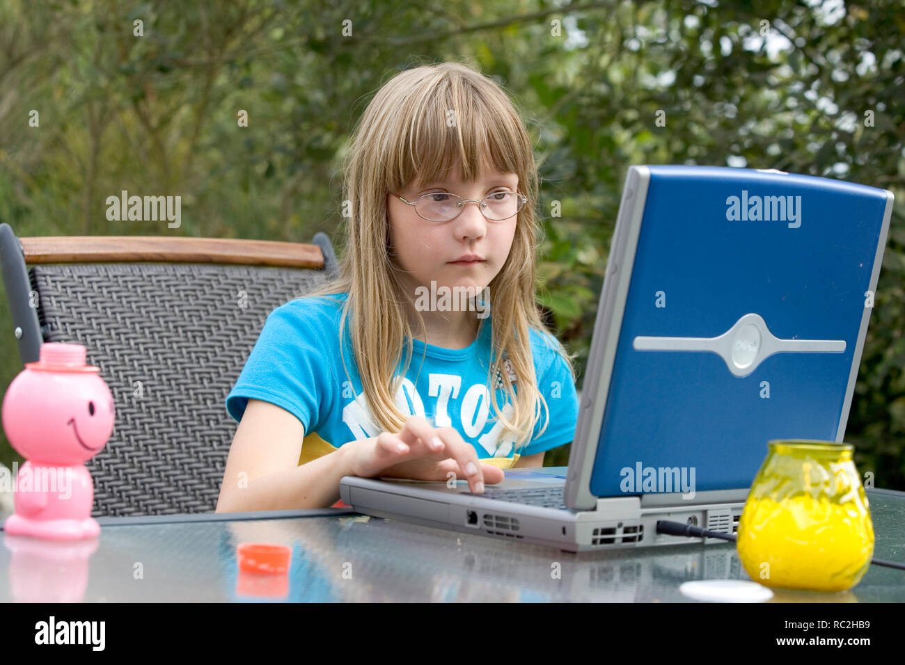 Los jóvenes caucásicos infantil femenina en los 2000s, jugando con un ordenador portátil en el jardín en verano. Foto de stock
