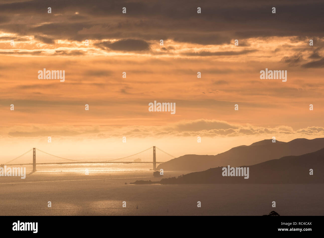 El puente Golden Gate en San Francisco, como visto desde lejos en el Berkeley Hills durante un hermoso atardecer cuando el cielo era de color naranja. Foto de stock
