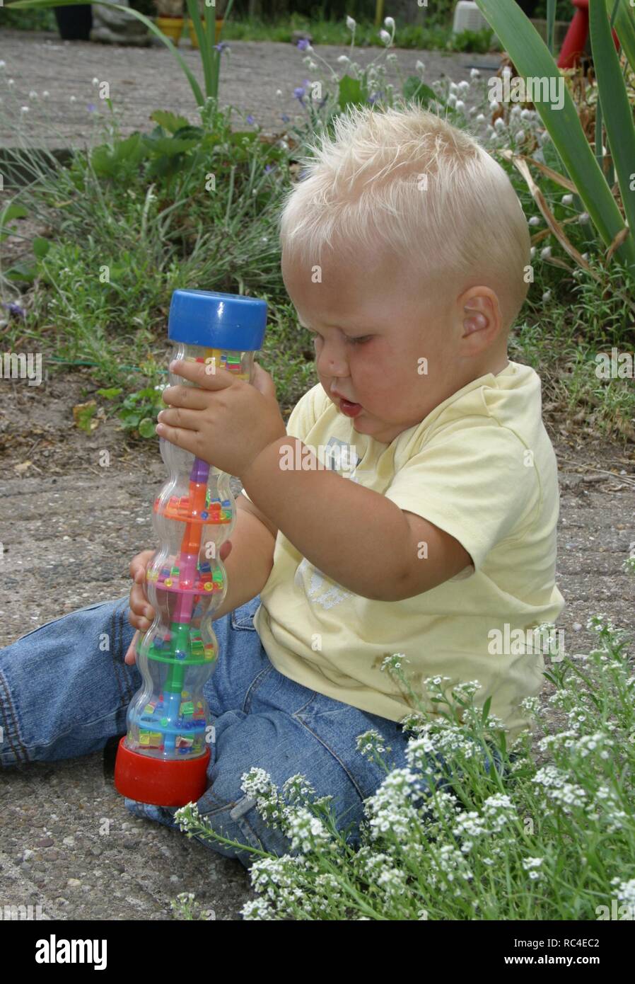 Chico jugando con el juguete en jardín en verano Foto de stock
