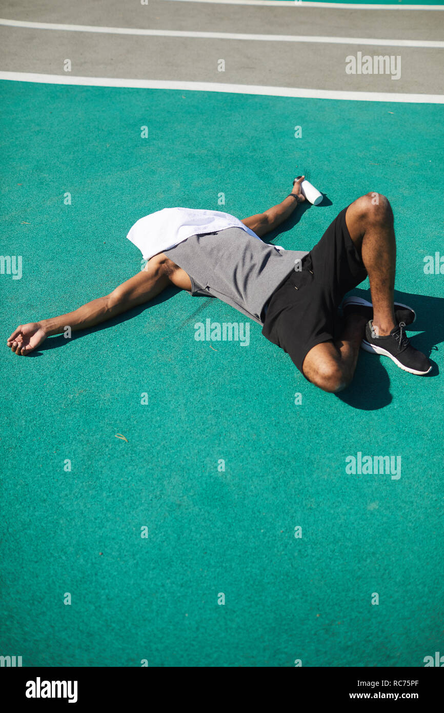 Agotado hombre negro acostado en el suelo del estadio Foto de stock