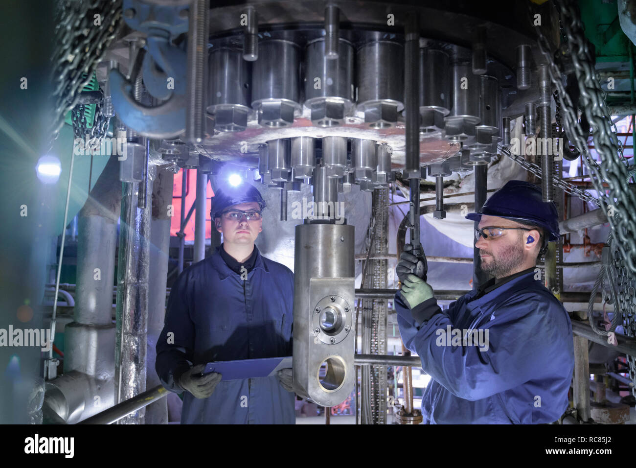 Los ingenieros que trabajan en espacio reducido bajo la turbina durante la parada en la estación de energía nuclear Foto de stock
