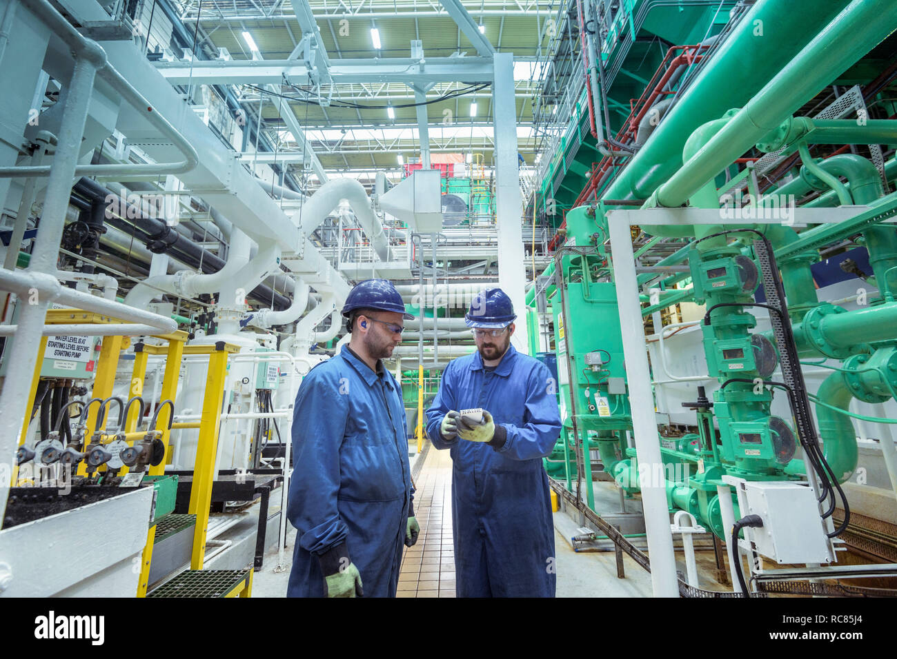Ingenieros en la sala de turbinas en la estación de energía nuclear Foto de stock