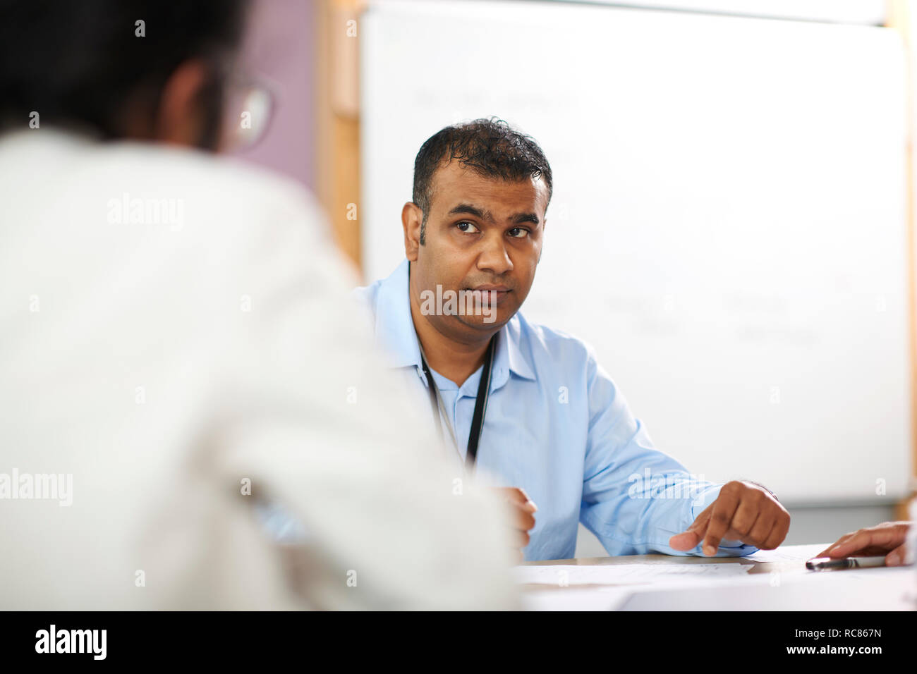 Profesor hablando con estudiantes universitarios en el aula Foto de stock