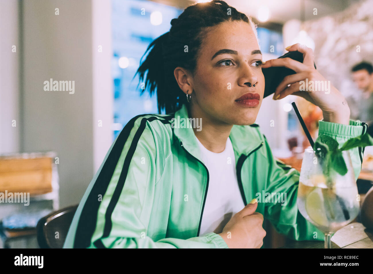 Mujer escuchando al mensaje en el móvil mientras beben en bares Foto de stock