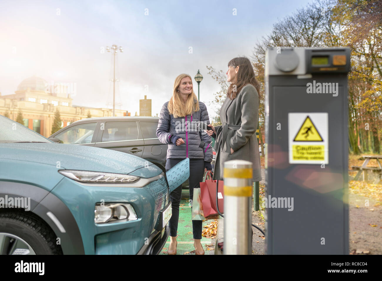 Los compradores femenino coche eléctrico de carga en el punto de carga, Manchester, Reino Unido Foto de stock