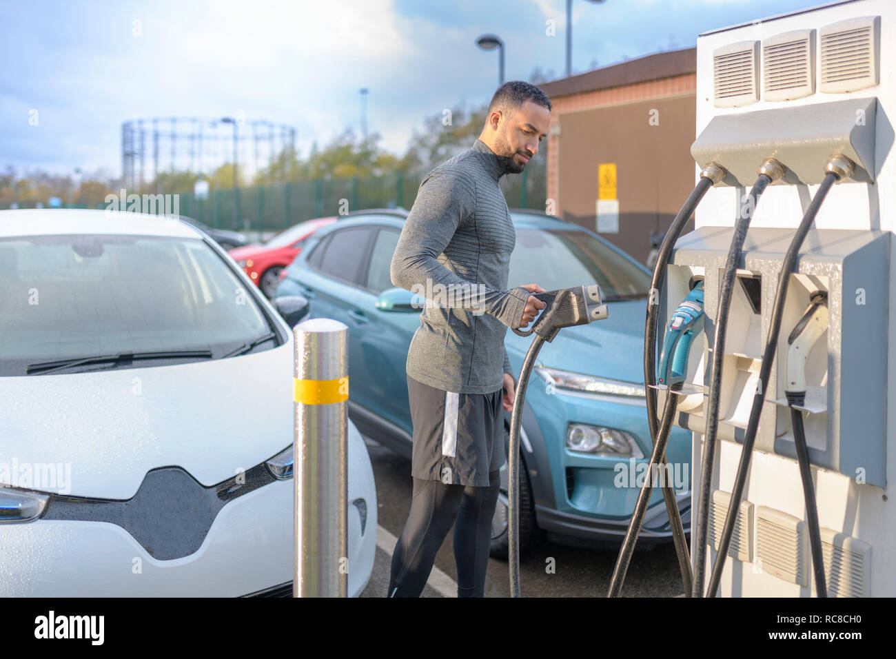 Deportista en el punto de carga de coches eléctricos, Manchester, Reino Unido Foto de stock
