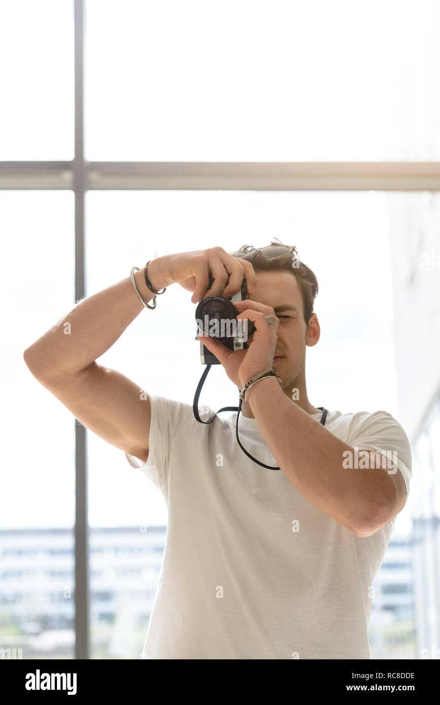 El hombre toma de fotografía, pared de vidrio en el fondo Foto de stock