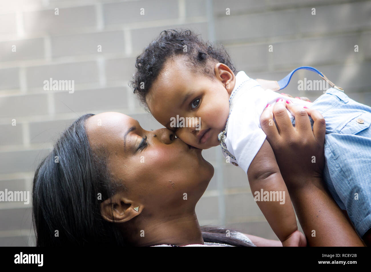 Cerrar negro de la madre y el bebé niña fuera besos Foto de stock