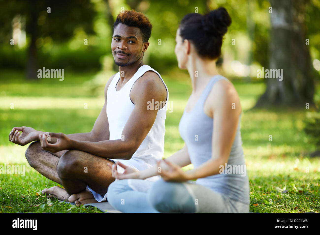 Contenido pareja interracial hablando durante la práctica de yoga al aire libre Foto de stock