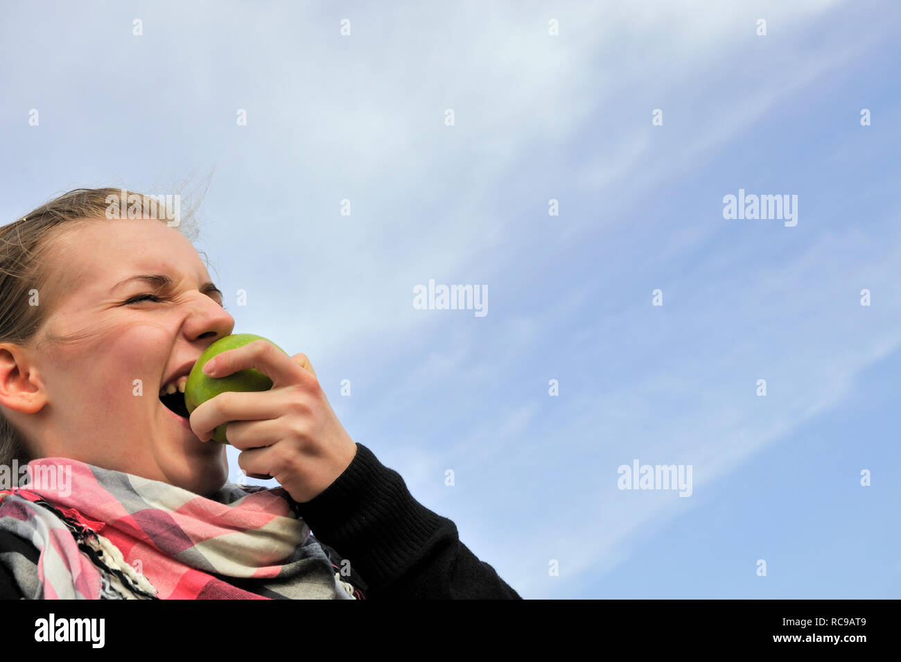 Frau Junge beisst en einen grünen Apfel - in den Apfel beissen sauren | joven comiendo una manzana verde - para tragar una píldora amarga o sujete la natt Foto de stock