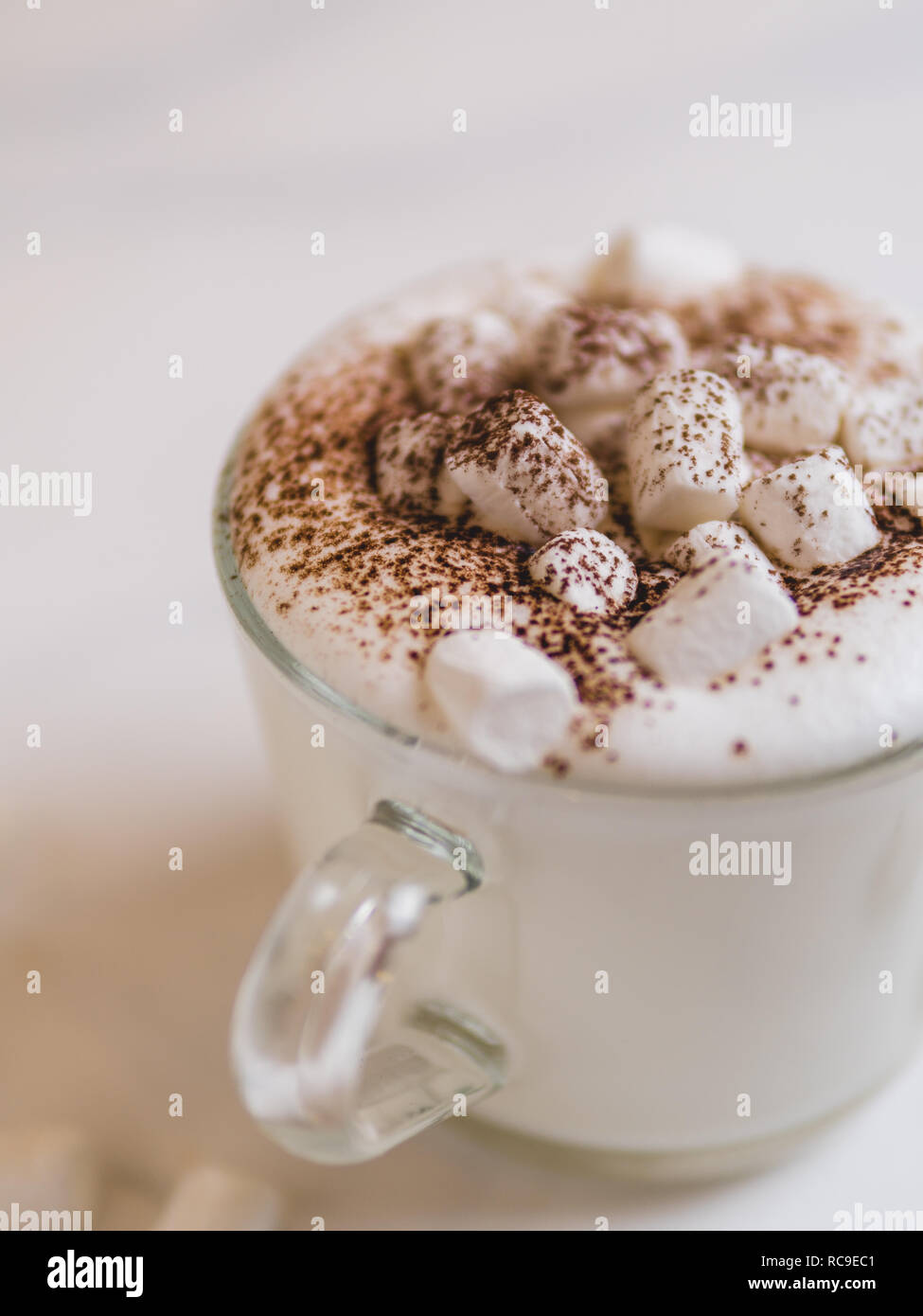 Babyccino - leche o nata batida con cacao o canela en polvo y malvavisco.  Idea y receta para niños - Bebida caliente leche batida,sin café. Babyccino  en un vaso sobre la mesa