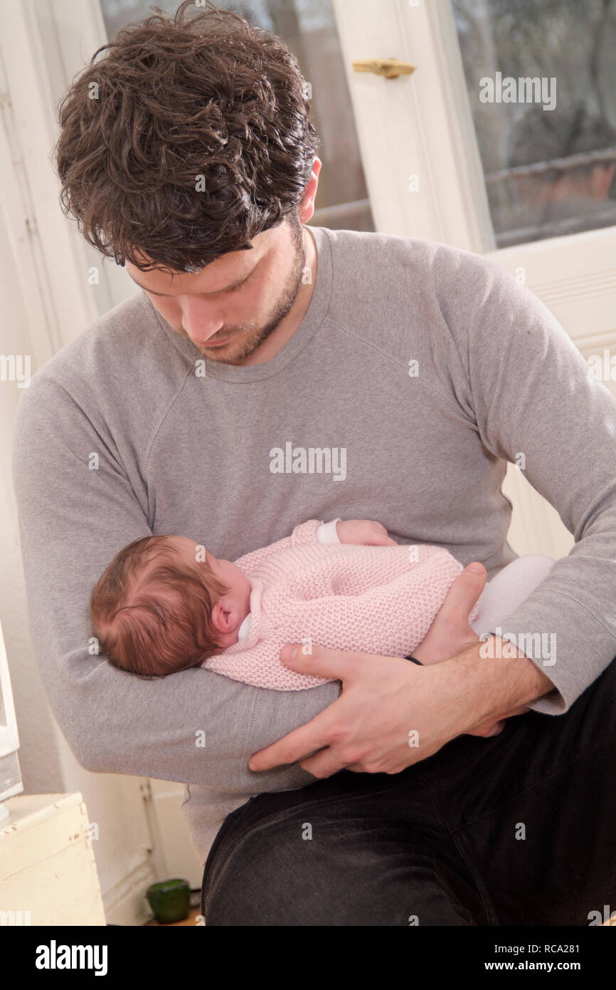 Junger hält seine Tochter neugeborene im, brazo tipo das ist 12 Tage alt | padre joven sosteniendo a su bebé recién nacido en sus brazos - el bebé ist 12 días de antigüedad. Foto de stock