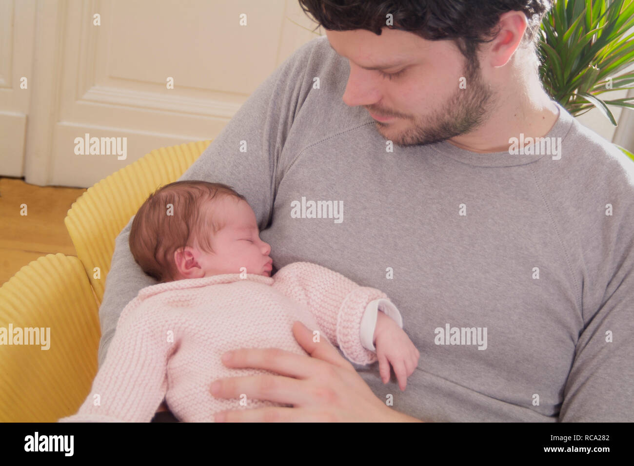 Junger hält seine Tochter neugeborene im, brazo tipo das ist 12 Tage alt | padre joven sosteniendo a su bebé recién nacido en sus brazos - el bebé ist 12 días de antigüedad. Foto de stock