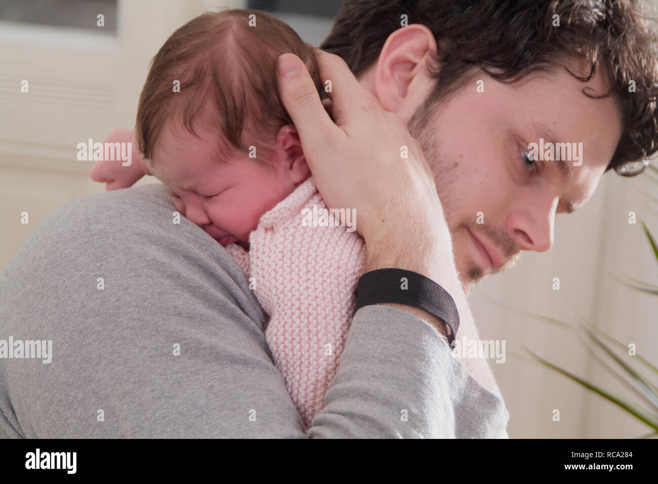 Junger hält seine Tochter neugeborene im, brazo tipo das ist 12 Tage alt | padre joven sosteniendo a su bebé recién nacido en sus brazos - el bebé ist 12 días de antigüedad. Foto de stock