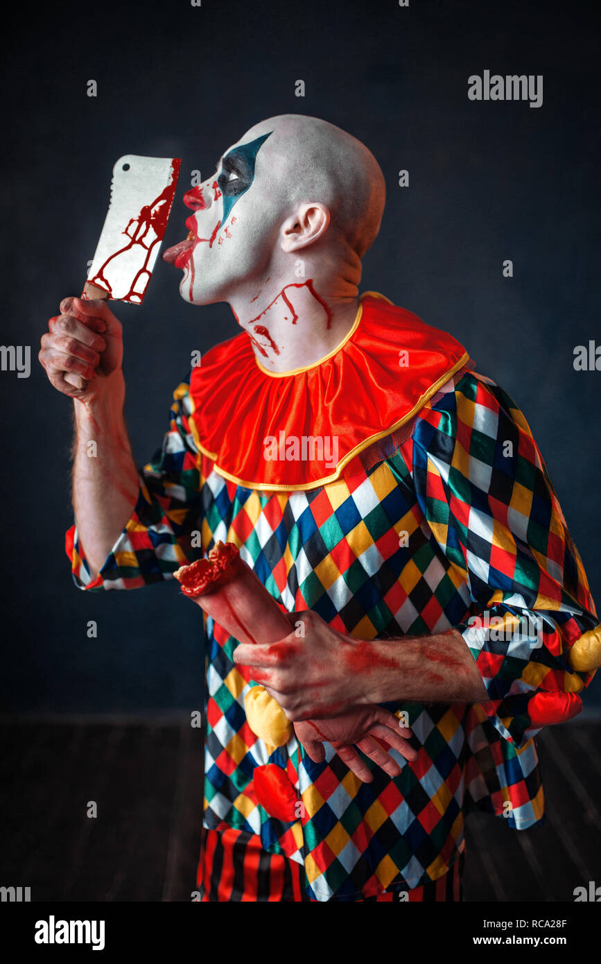 Terrorífico payaso sangriento lame la cuchilla. Hombre con maquillaje en  Halloween Costume, crazy maniac tiene la mano humana Fotografía de stock -  Alamy