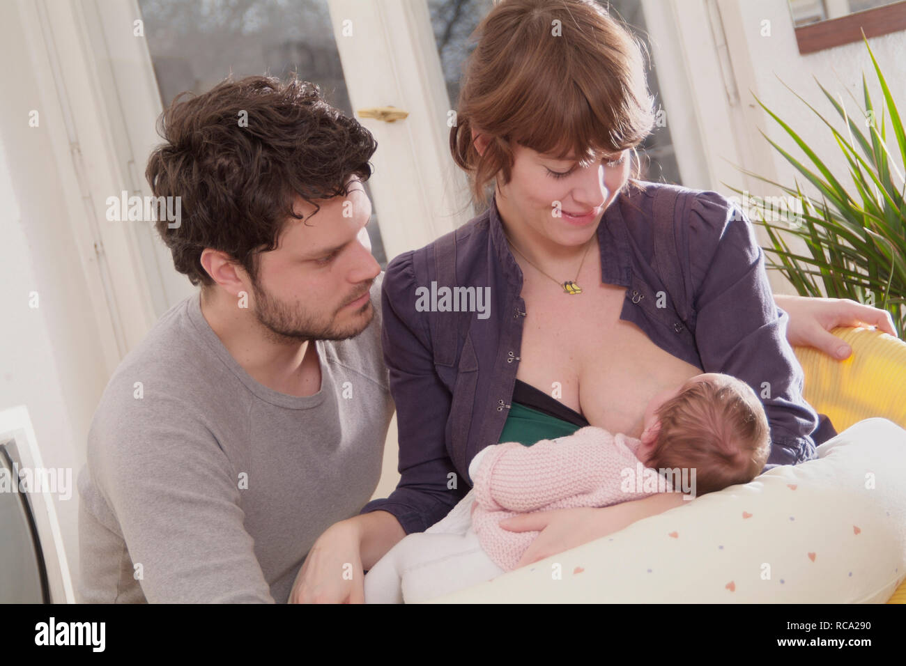 Junge Eltern beim Stillen ihrer neugeborenen Tochter, tipo das ist 12 Tage alt | los padres jóvenes, el cuidado de su bebé recién nacido - el bebé ist 12 días de edad. Foto de stock