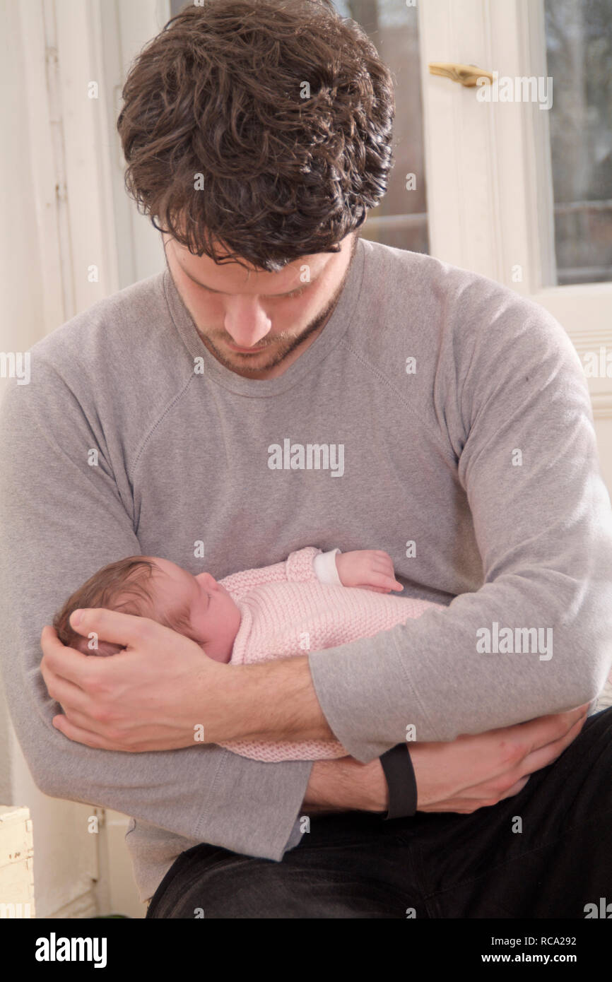 Junger hält seine Tochter neugeborene im, brazo tipo das ist 12 Tage alt | padre joven sosteniendo a su bebé recién nacido en sus brazos - el bebé ist 12 días de antigüedad. Foto de stock