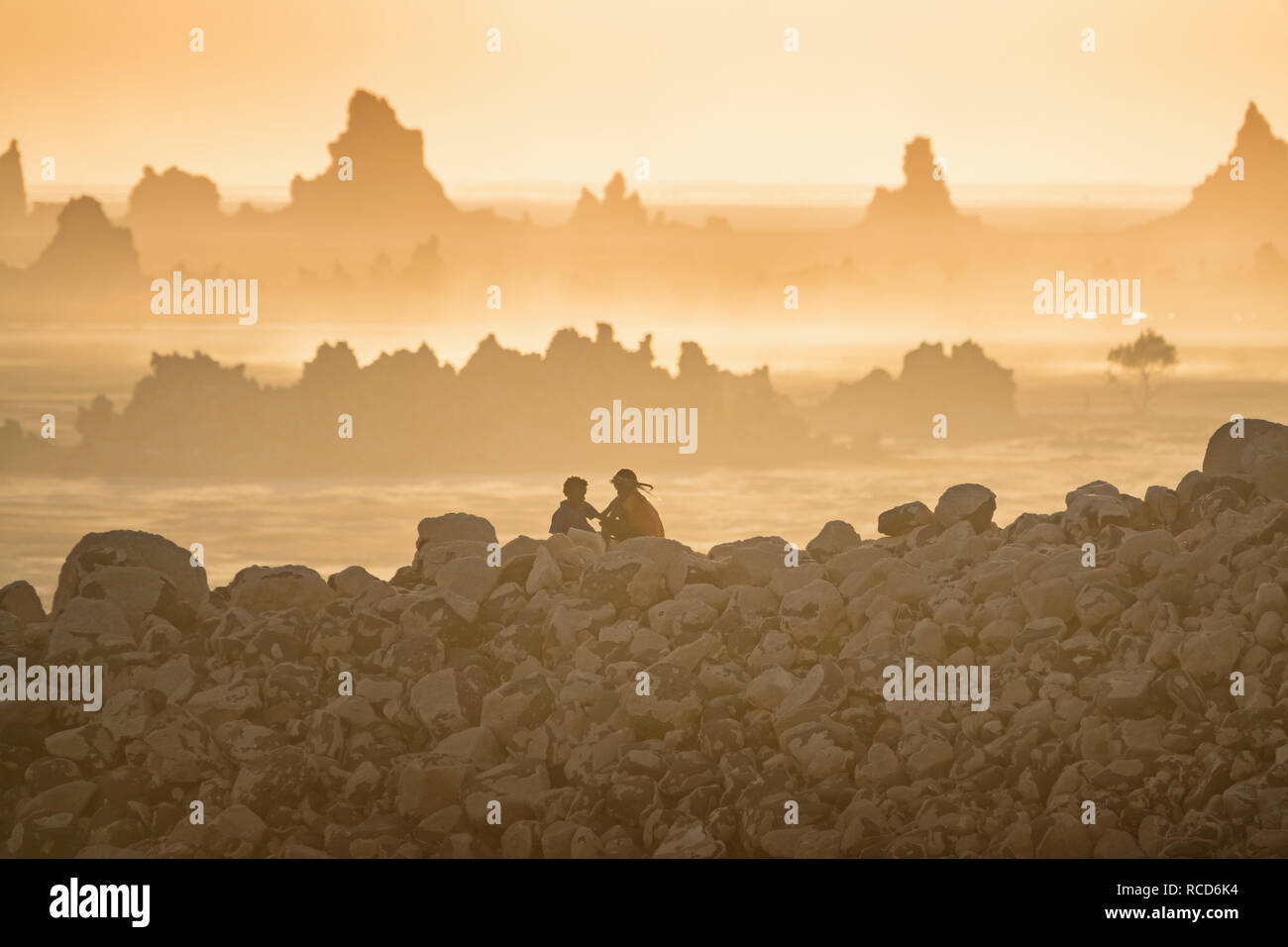 Los niños juegan en el lago Abbe, Djibouti con chimeneas de piedra caliza en el fondo al atardecer. Foto de stock